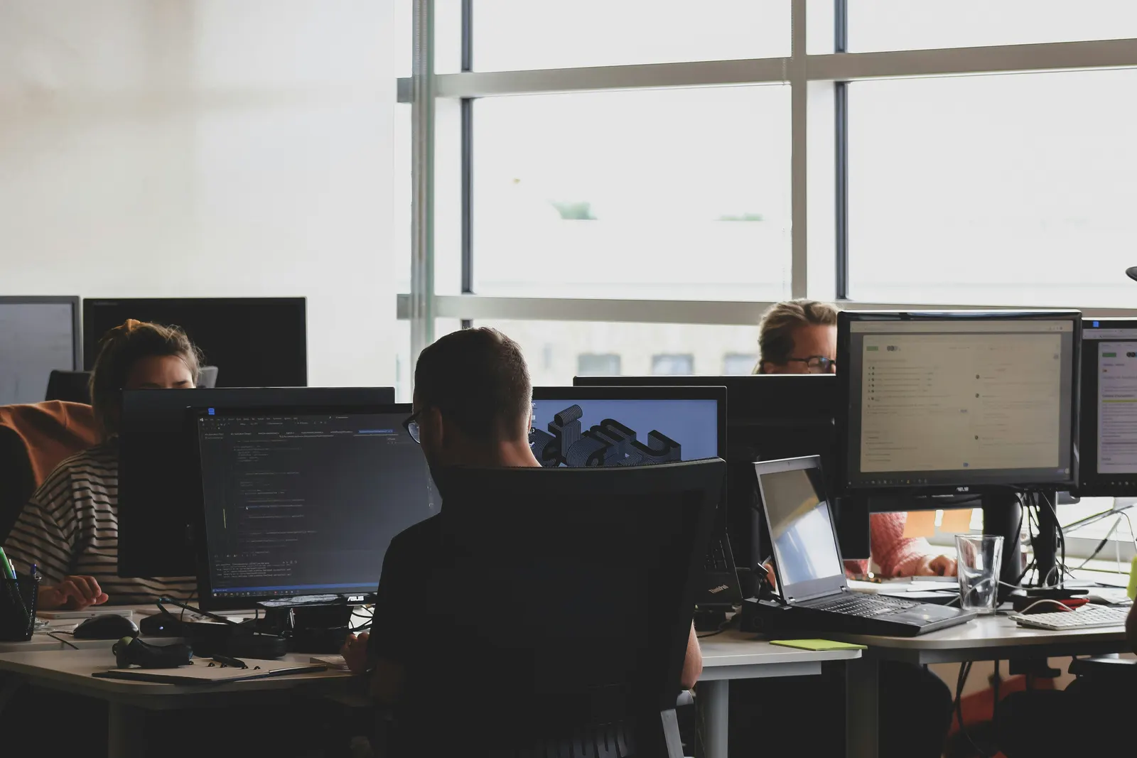 Équipe au travail sur plusieurs écrans en open space